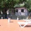 Terrazza con lettini prendisole, alberi e edificio sullo sfondo.