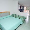 Una camera con letto matrimoniale, letto singolo e tavolo da pranzo, vista su balcone.