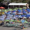 Spiaggia affollata con molti ombrelloni blu e gialli, area di relax.