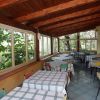 Una veranda con tavoli a quadretti, sedie colorate e finestre ampie.