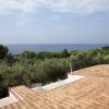 Vista del mare e alberi dalla cima di un edificio con tetto di tegole.