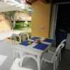 Tavolo bianco con quattro sedie e tovagliette blu su una veranda.