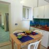 Angolo cucina con tavolo apparecchiato e porta verso zona notte con letto.