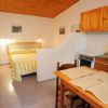 Camera con letto a righe gialle e angolo cottura in legno chiaro.