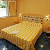 Camera con letto matrimoniale a righe gialle, pareti arancioni, pavimento blu e finestra aperta.