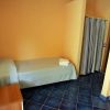 Camera con letto singolo coperto da trapunta azzurra, pavimento blu e tende a righe.