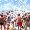 Festa in spiaggia con schiuma e molte persone.