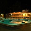 Una piscina illuminata di notte con ombrelloni e tavoli apparecchiati vicino.