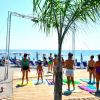 Persone partecipano a un'attività di gruppo su una piattaforma di legno in spiaggia.