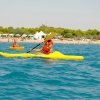 Persone in kayak gialli remano in mare vicino alla spiaggia.