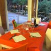 Tavolo apparecchiato con tovaglia arancione e sedie colorate in un ristorante all'aperto.