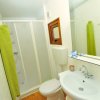 Bagno con doccia, lavandino e WC. Asciugamano verde appeso accanto alla doccia.