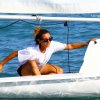 Persona in barca a vela sul mare, vestita con maglietta bianca e occhiali da sole.