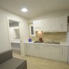 Cucina moderna con armadietti bianchi, piano cottura e frigorifero.