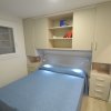 Camera da letto con letto matrimoniale, armadi beige e scaffali.