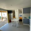 Sala con cucina, tavolo bianco e accesso a terrazza esterna.