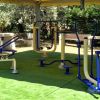Area fitness all'aperto con attrezzi blu e crema.