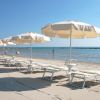 Spiaggia con lettini e ombrelloni bianchi.