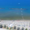 Spiaggia con ombrelloni bianchi e mare calmo.