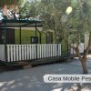 Casa mobile con terrazza coperta e recinto bianco.