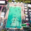 Piscina vista dall'alto con bagnanti e lettini.