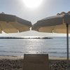 Spiaggia con due ombrelloni e mare al tramonto.