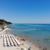 Spiaggia con ombrelloni bianchi e mare azzurro.