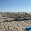 Spiaggia con file di ombrelloni chiusi.