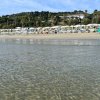 Mare limpido e stabilimento balneare sullo sfondo.