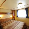 Una camera da letto con letto matrimoniale, mobili in legno chiaro e finestre con tende blu.