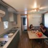 Interno di una roulotte con cucina e tavolo. Due persone mangiano insieme.