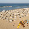 Spiaggia con ombrelloni bianchi e area giochi.