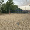 Campo da beach volley vuoto con rete blu e pali rossi.