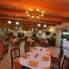 Interno di ristorante con tavoli apparecchiati e soffitto in legno.