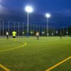 Un campo da calcio illuminato di notte con giocatori sul terreno di gioco.