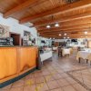 Un'ampia sala ristorante con tavoli apparecchiati e un bancone di legno.