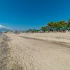 Una lunga spiaggia di sabbia con ombrelloni e mare calmo.