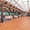 Sala ristorante coperta con tavoli apparecchiati e sedie bianche.