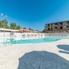Piscina all'aperto con sdraio, edificio a tre piani sullo sfondo.