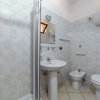Un bagno con doccia, lavabo, bidet e WC. Piastrelle chiare e specchio sopra il lavabo.