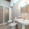 Bagno con doccia, lavabo, bidet e WC. Piastrelle beige e specchio con luce.