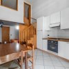 Cucina con tavolo, sedie, mobili bianchi, fornello e scala in legno.