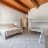 Una camera con letto matrimoniale e letti a castello, soffitto in legno e pavimento piastrellato.