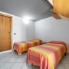 Due letti singoli con coperte a righe arancioni e rosa, porta in legno, soffitto inclinato.