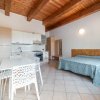 Camera con angolo cottura, tavolo bianco, sedie traforate, letto matrimoniale.