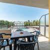 Balcone con tavolo e sedie in plastica nera vista su piscina e vegetazione.