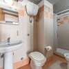 Bagno con wc, bidet, lavandino e box doccia, piastrelle bianche e arancioni.