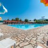 Una piscina circondata da lettini e ombrelloni colorati sotto un cielo blu.