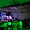 Uno spettacolo serale in un teatro con spettatori seduti e persone sul palco.