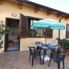 Spazio esterno con tavolo, sedie e ombrellone verde, davanti a una casa con porte aperte.